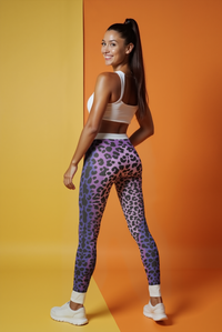Back view of a model in Trendy Women's Animal Print Leggings, exhibiting a stylish leopard print design with an orange background.