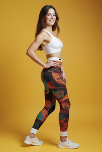 A woman showcasing Bohemian Printed Leggings while smiling, set against a vivid yellow backdrop, ideal for both workouts and stylish casual wear.