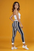 Model smiling while wearing Casual Striped Leggings and a white crop top, set against a bright yellow backdrop, emphasizing comfort and style for activewear.